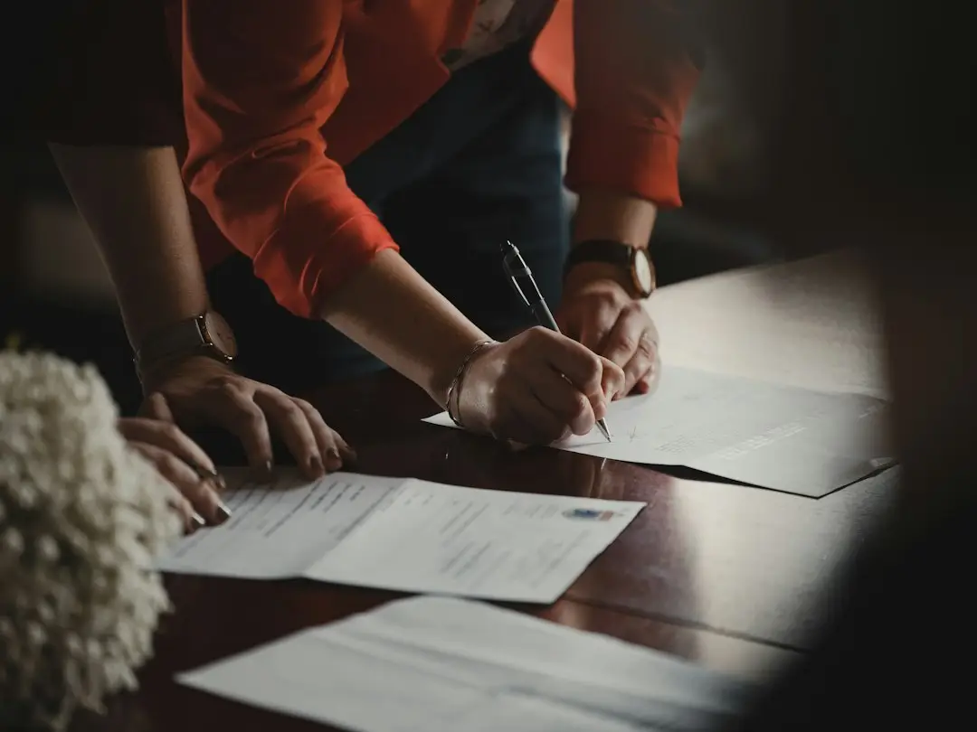 A person writing on a paper form with a pen, such as advance directives