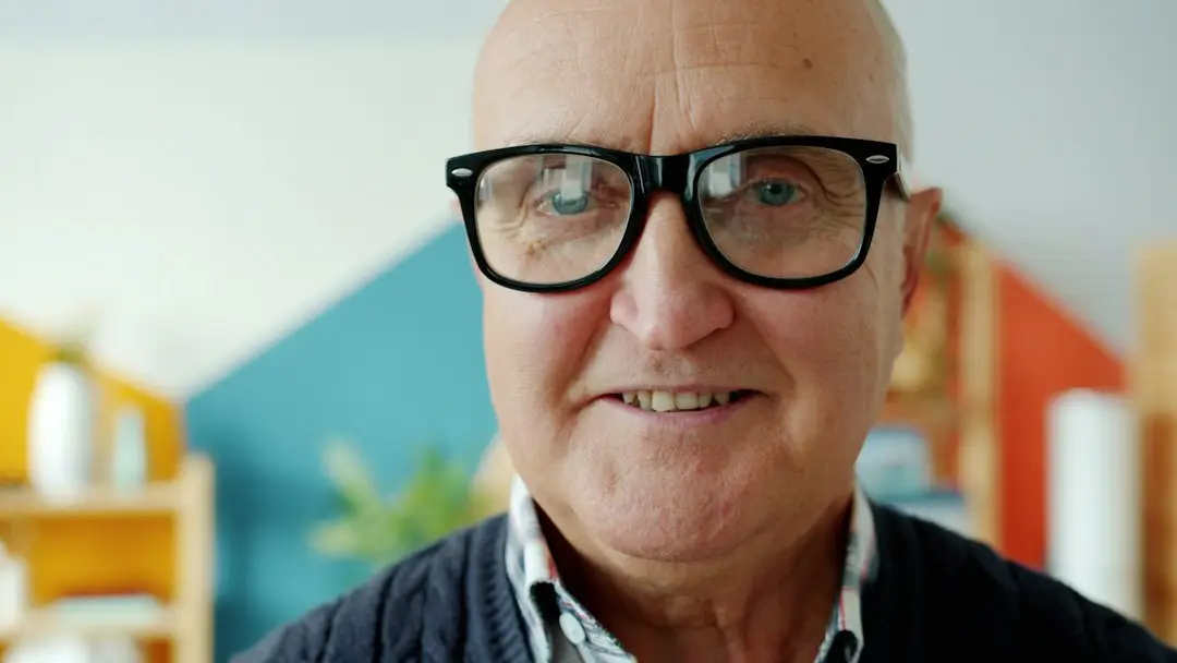 A smiling older man with glasses thinking about his PSA decision