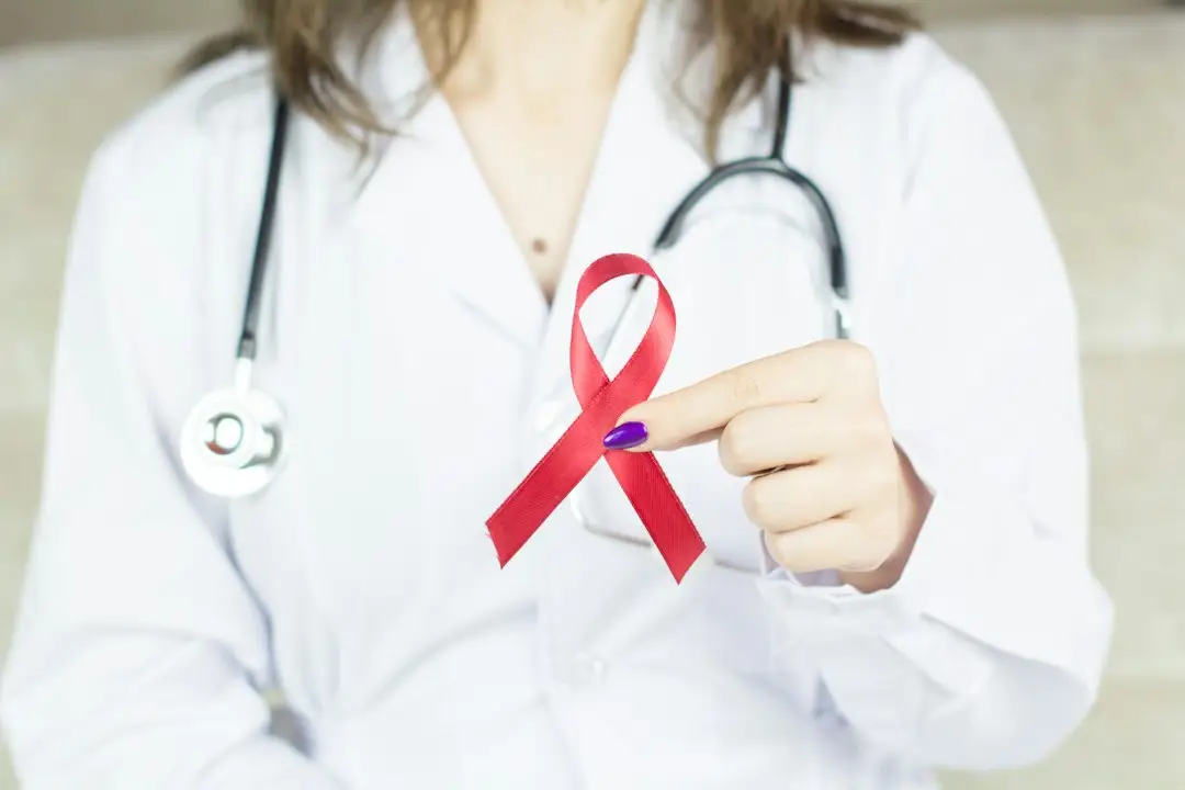 A woman in a white shirt holding a red HIV awareness ribbon, a symbol of HIV and PrEP for women