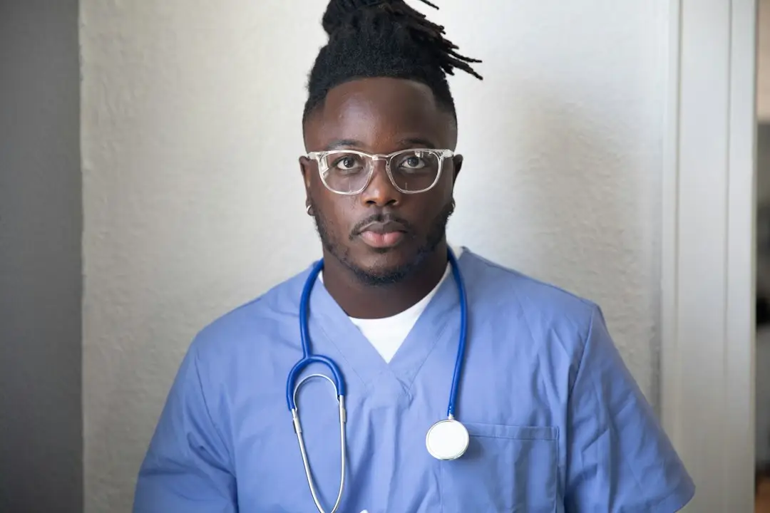 A young man in a blue shirt and glasses, representing people living with sickle cell