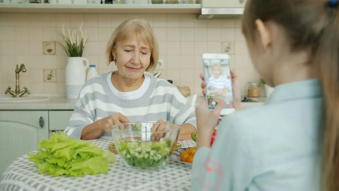 An older woman and a younger woman preparing a salad together in a home kitchen