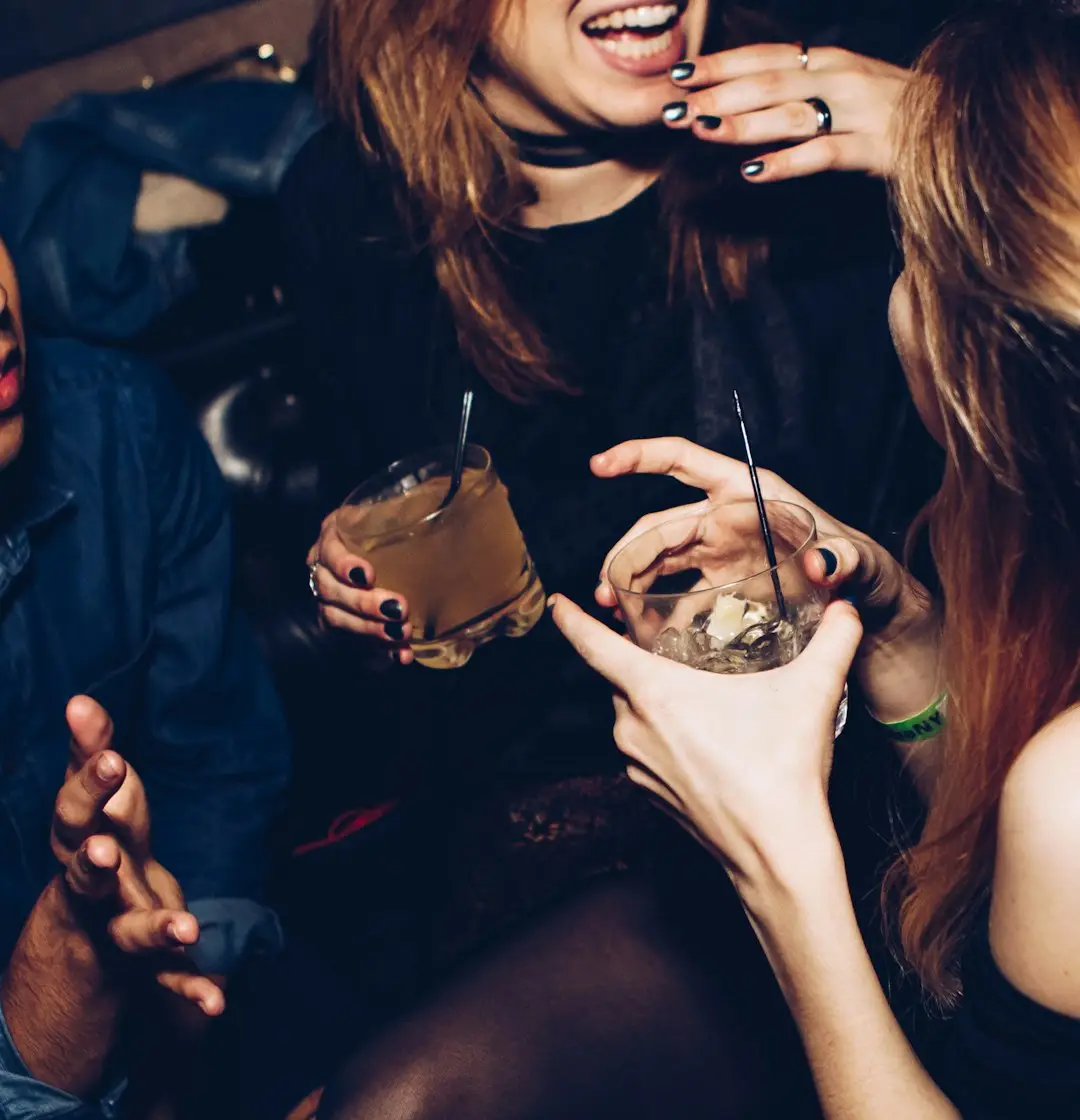 Two women talking and smiling while holding drinking glasses at a gathering